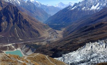 A stunning aerial view of the Himalayas with a glacial lake and rugged mountain terrain.