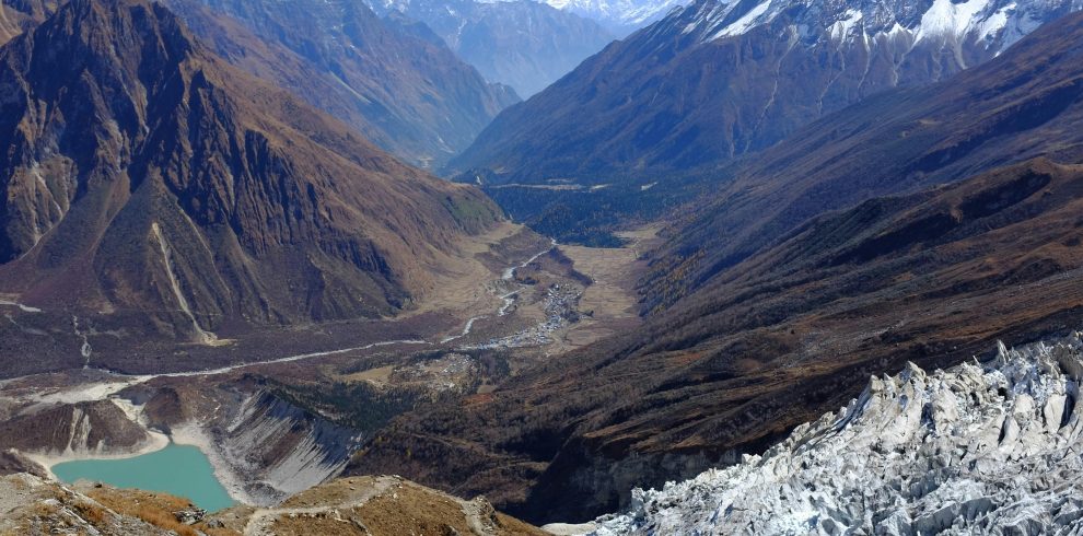 A stunning aerial view of the Himalayas with a glacial lake and rugged mountain terrain.